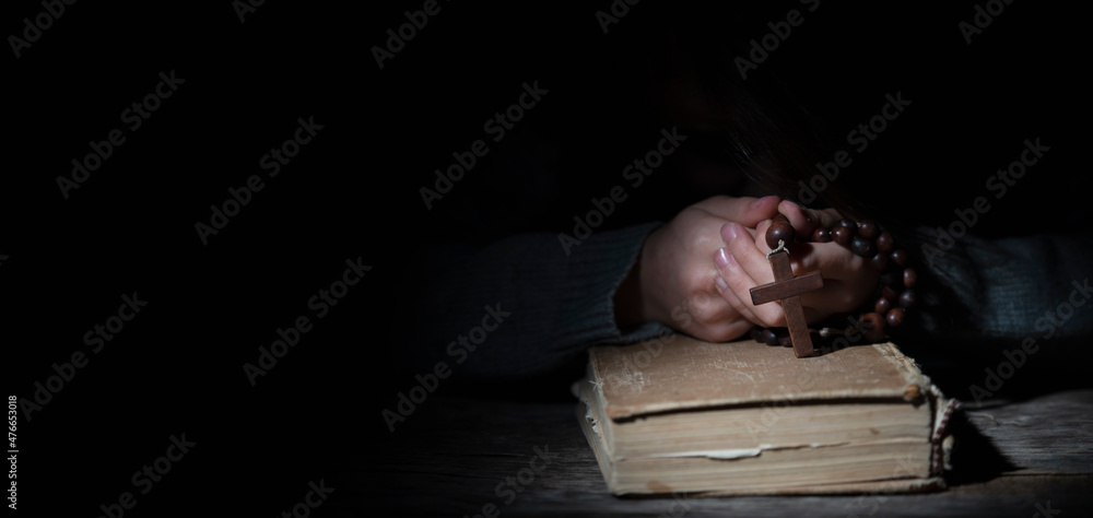 Obraz premium Young beautiful girl praying to God with wooden rosary. Copy space for text or design.