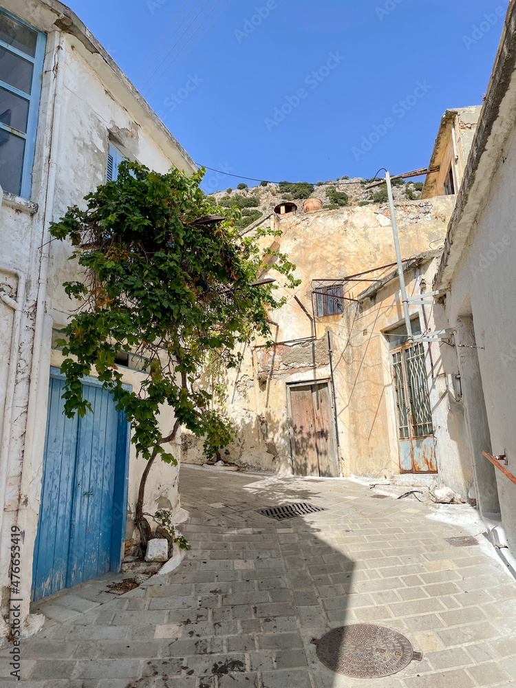 Eine kleine verwinkelte Gasse in einem Bergdorf auf Kreta, Griechenland mit altertümlichen Häusern und einer blauen Tür