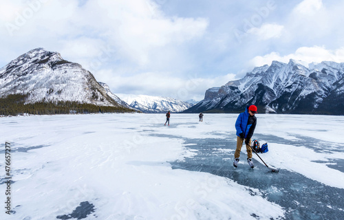Photography Boy Enjoying Frozen Lake Minnewanka in Banff National Park With His Ice Hockey S