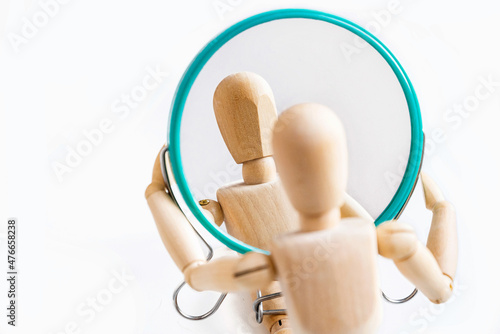 Wooden dummy looks at its reflection in the mirror