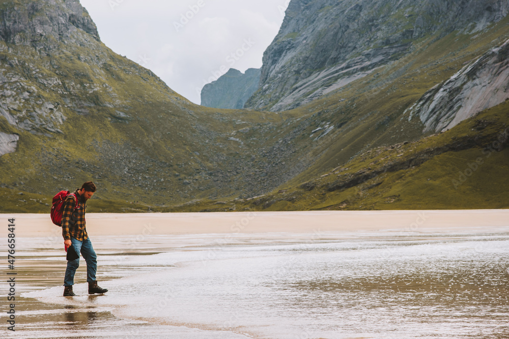 Man hiking solo in Norway travel adventure vacations outdoor active healthy lifestyle tourist backpacking on sandy Horseid beach Lofoten islands