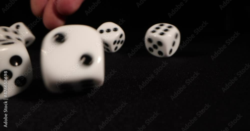 Rolling White dice on a black background. Hand dropping dice. Macro shot, side-view camera tracking. 4k Rolling White dice on a black background. Hand dropping dice. Macro shot, side-view camera tracking. 4k