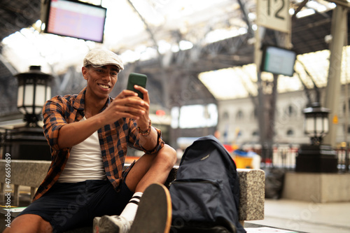  Happy young man waiting for the train. African man waiting in a subway. Man using a phone