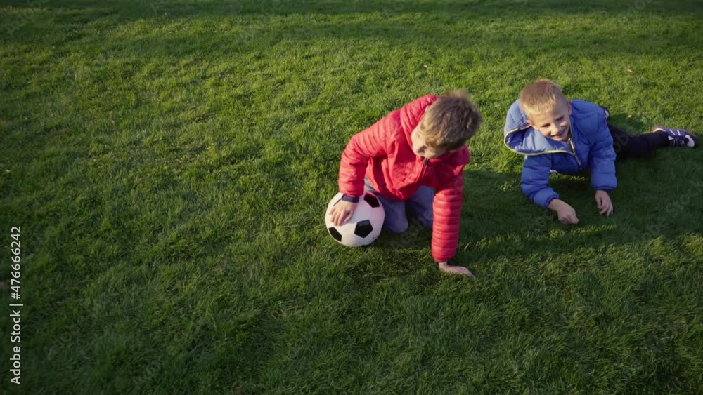 School friends are playing with a soccer ball on the lawn. The brothers are having fun on the green grass. Friendship concept. School friends are playing with a soccer ball on the lawn. The brothers are having fun on the green grass. Friendship concept.