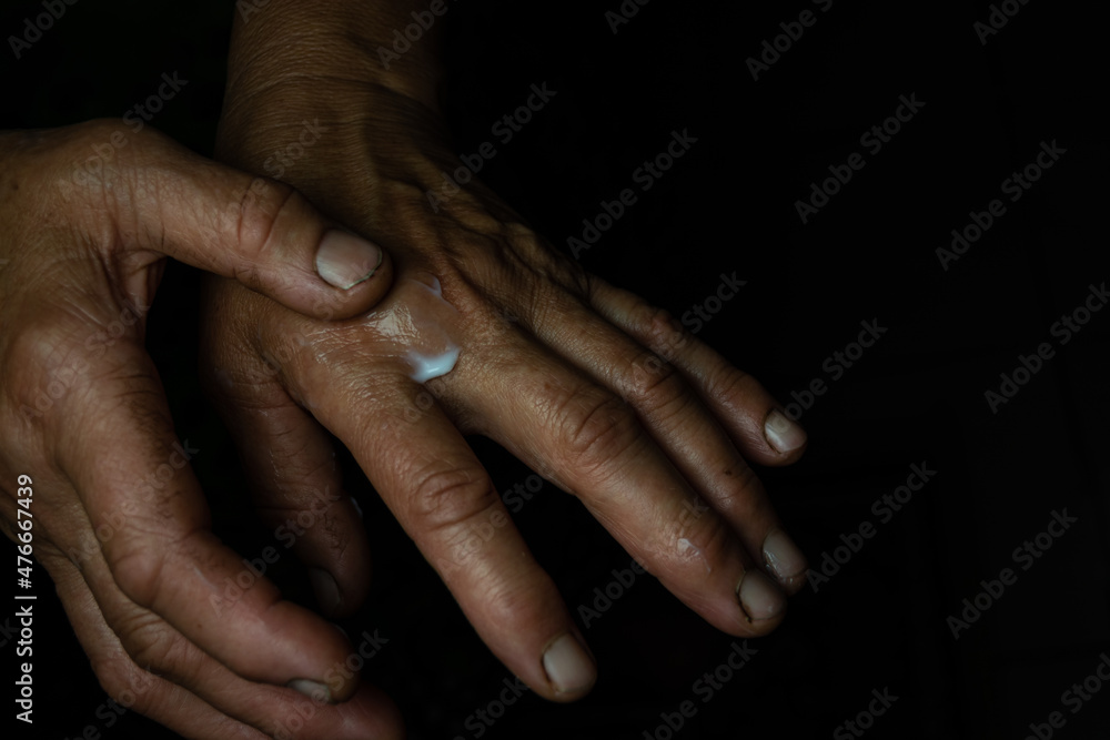 Fototapeta premium An elderly woman rubs hand cream into wrinkled skin.