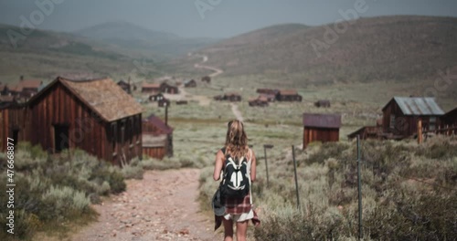 Female hiker with backpack exploring the gold mining ghost town of Bodie, California in the summer