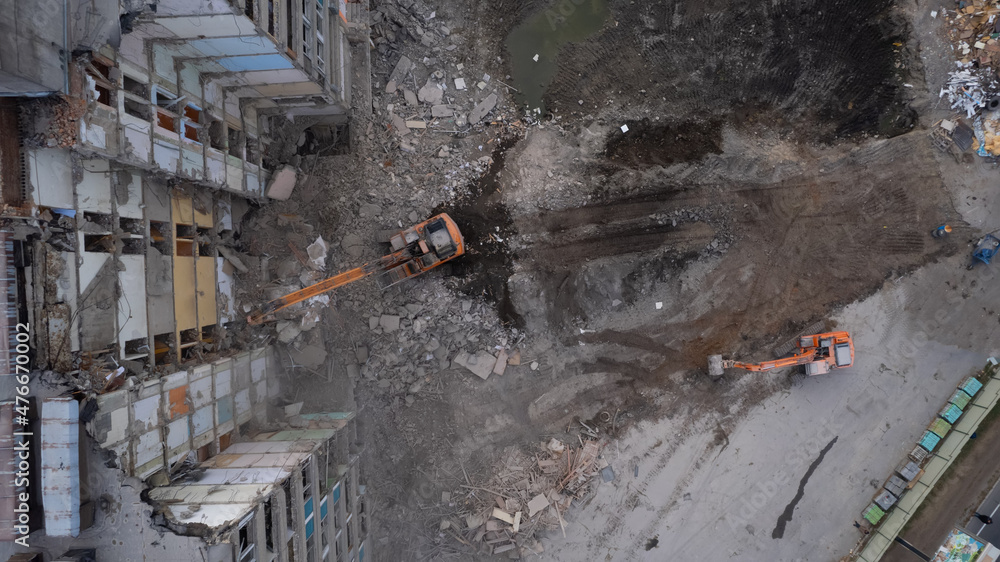 Obraz premium Excavator for dismantling buildings, using a special claw, dismantles a multi-storey building. View from above