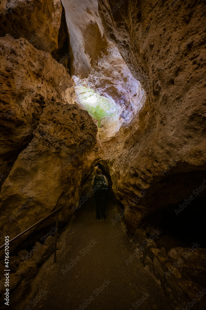 Hiker Looks Up at Cave Wall Before Tunnel