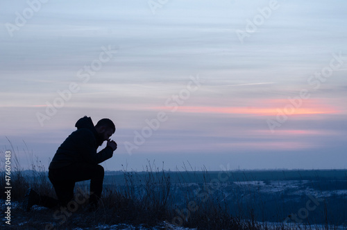 Prayer. Repentance. A man on his knees. Prayer. Silhouette of a man on a blue sky background. Kneeling Prayer to God. Glorification. Praising God. Christian photo