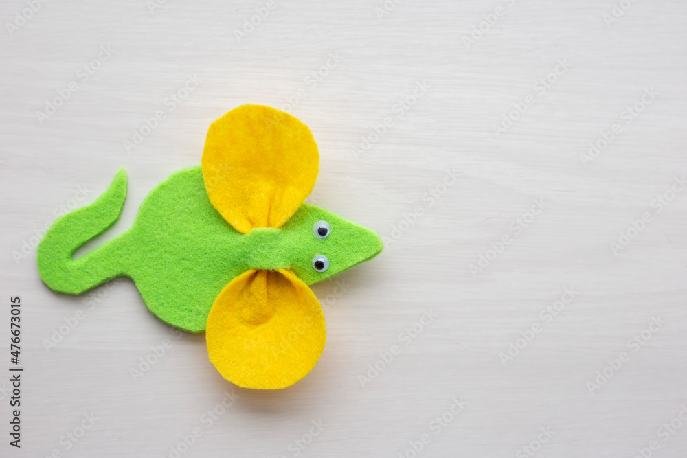 Naklejka premium Handmade felt mouse on a light background. Toy mouse made of green and yellow felt