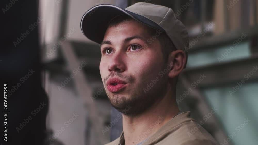 Young craftsman in cap nodding and talking while discussing project with client during work in professional workshop
