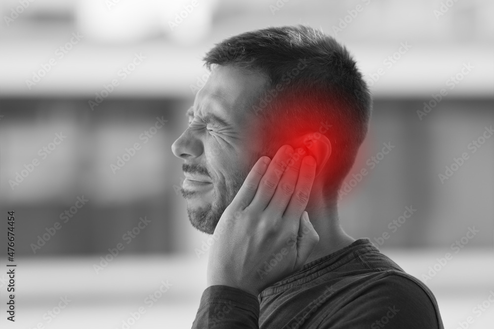 Young man suffering from of strong earache or ear pain. Ear diseases - obrazy, fototapety, plakaty 