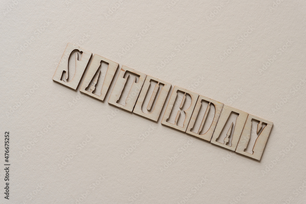 the word "saturday" (day of the week) in wooden stencil font on textured ivory paper - obrazy, fototapety, plakaty 
