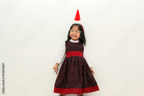 Latin little girl with elegant party dress and Christmas hat dances with happiness for the arrival of December and celebrate Christmas the new year  © Arlette