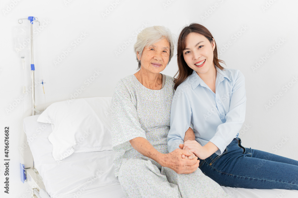 Obraz premium old asian patient sick and admit in hospital, young asian female visiting old female, they holding hands together, they feeling happy and smile, elderly healthcare