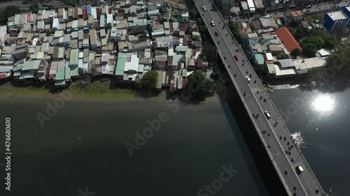 Aerial shot above a busy traffic bridge and waterfront shanty town houses along Kenh Te canal in Ho Chi Minh City, Vietnam on a sunny day. photo