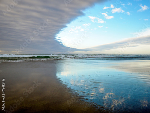 View of Piha Beach, Auckland, New Zealand with reflections and evening clouds