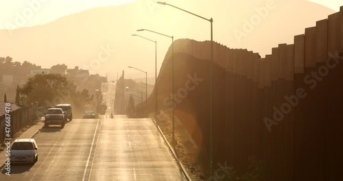Tecate, Baja California, Mexico - September 14, 2021: Late afternoon sun shines on the USA Mexico border wall as it winds through Tecate. photo