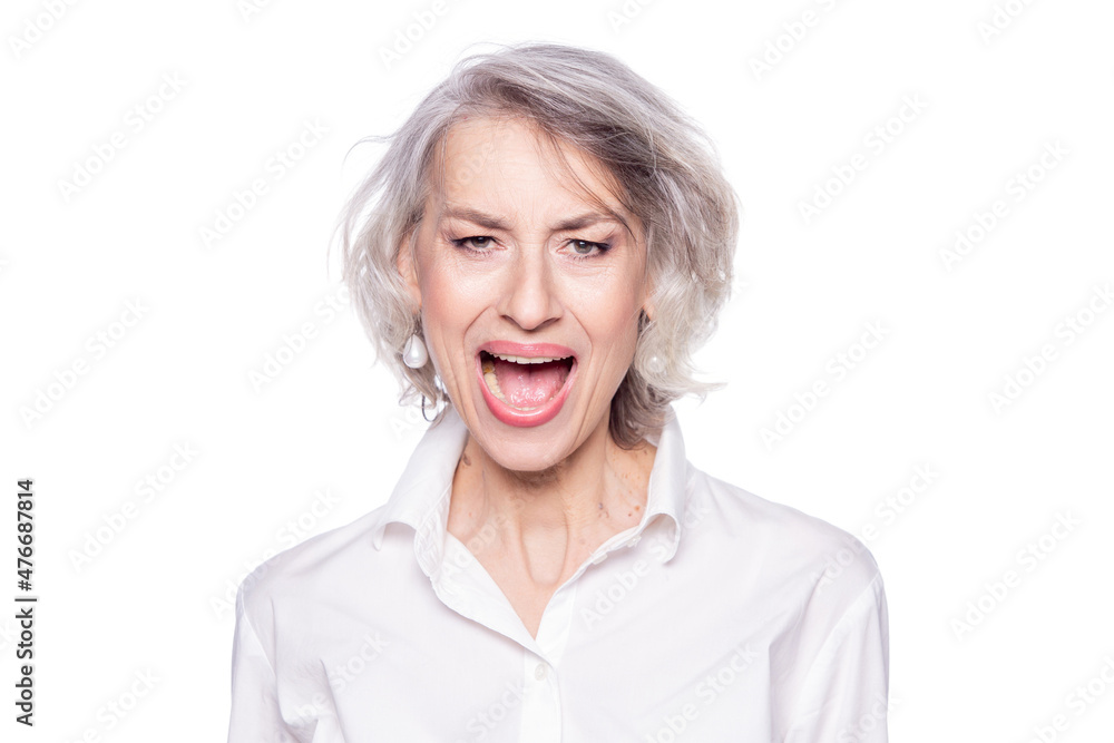 Photo of mature beautiful grey-haired woman yelling and screaming loudly with a wide open mouth with an angry expression isolated on white background Photo of mature beautiful grey-haired woman yelling and screaming loudly with a wide open mouth with an angry expression isolated on white background