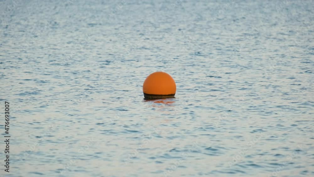 Orange buoy floating on sea surface waves. Human life safety concept Orange buoy floating on sea surface waves. Human life safety concept