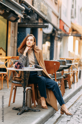 Photography Portrait of a young girl in a brown coat on the background of the Galata Tower
