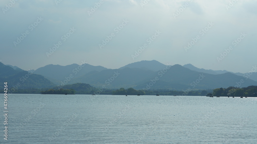 The beautiful lake landscapes in the Hangzhou city of the China in spring with the peaceful lake and fresh green mountains The beautiful lake landscapes in the Hangzhou city of the China in spring with the peaceful lake and fresh green mountains