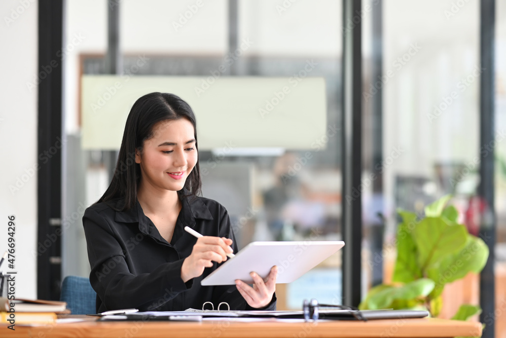Cheerful female office worker working with digital tablet at modern office. Cheerful female office worker working with digital tablet at modern office.