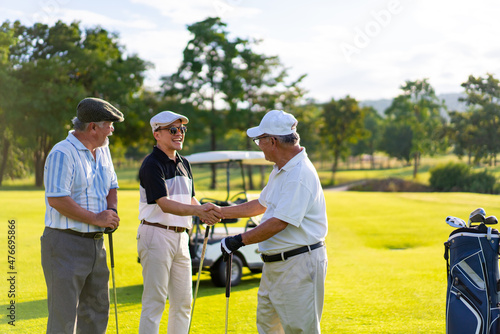 Group of Asian people businessman and senior CEO enjoy outdoor sport lifestyle golfing together at golf country club. Healthy men golfer shaking hand after finish game on golf course at summer sunset