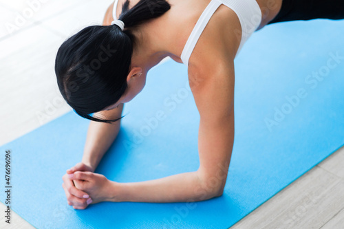 Slim fitnes young girl doing planking exercise indoors at home gymnastics