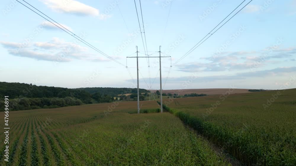 Tower with electric power lines for transfering high voltage electricity located in agricultural cornfield. Delivery of electrical energy concept Tower with electric power lines for transfering high voltage electricity located in agricultural cornfield. Delivery of electrical energy concept