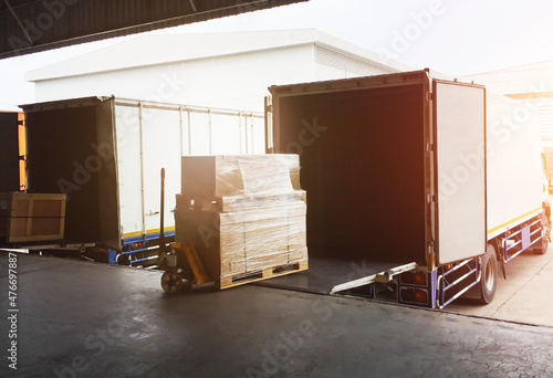 Cargo Package Boxes Loading into Shipping Cargo Container. Trucks Parked Loading at Dock Warehouse. Commece Supply Chain Shipment Logistics Export-Import. Freight Truck Transportation	 photo