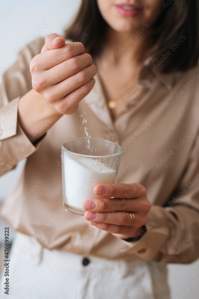 Vertical cropped shot of female artisan pouring dry mixture by hand into measuring transparent glass for creating candle building mixture. Process of making handmade natural candle at workshop. Vertical cropped shot of female artisan pouring dry mixture by hand into measuring transparent glass for creating candle building mixture. Process of making handmade natural candle at workshop.
