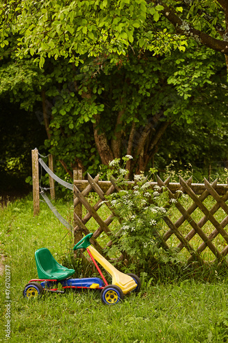 Kettcar auf Rasen vor Gartenzaun