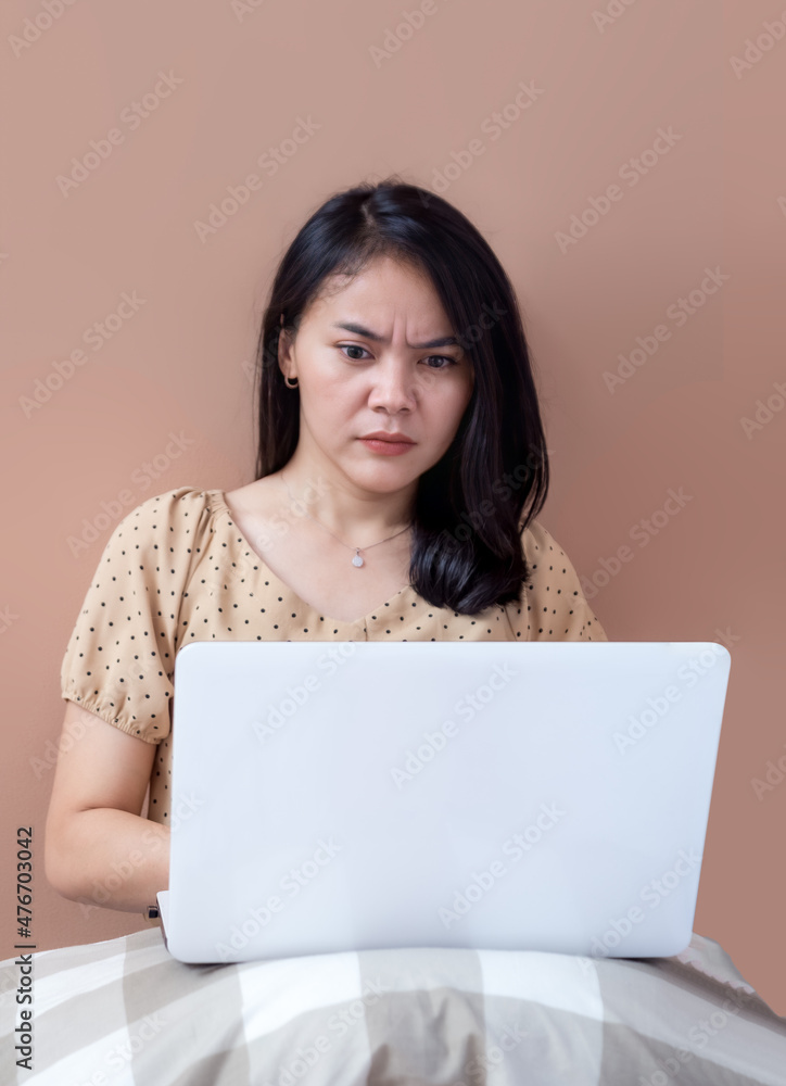 Naklejka premium Young woman in bed staring seriously at laptop screen
