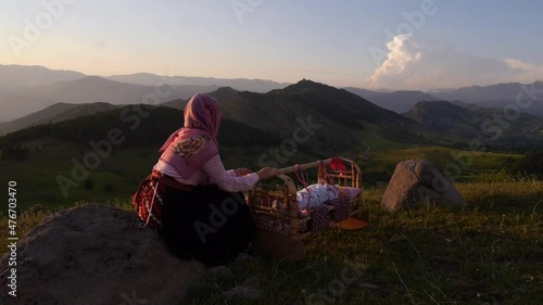 traditionally dressed Turkish woman rocking a cradle