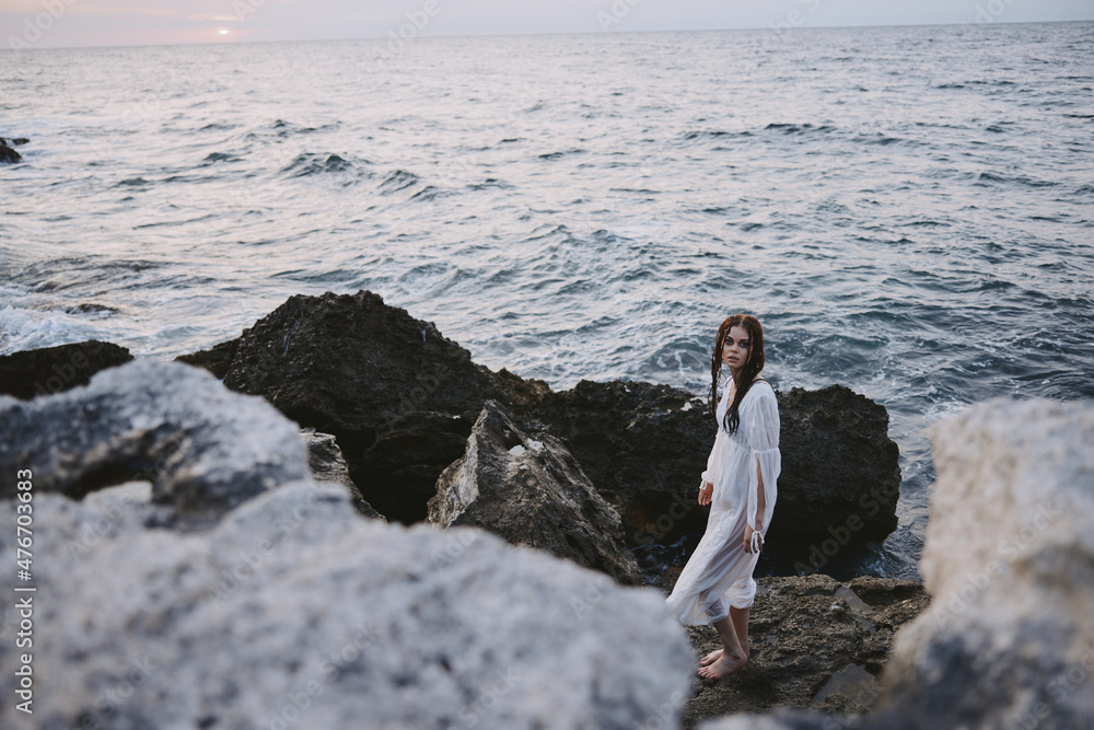 woman stands on rocks in white dress ocean nature travel