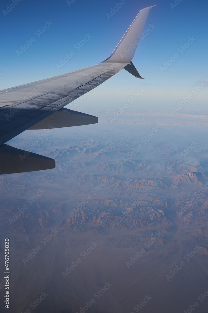 Obraz premium Beautiful high angel view at the mountains through the porthole of the plane. Travel cocept