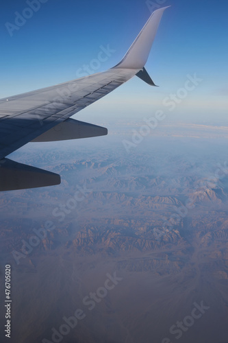 Beautiful high angel view at the mountains through the porthole of the plane. Travel cocept