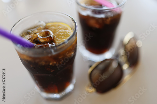 Pair of glasses filled with coca cola with lemon and ice cubes, cooling summertime drinks