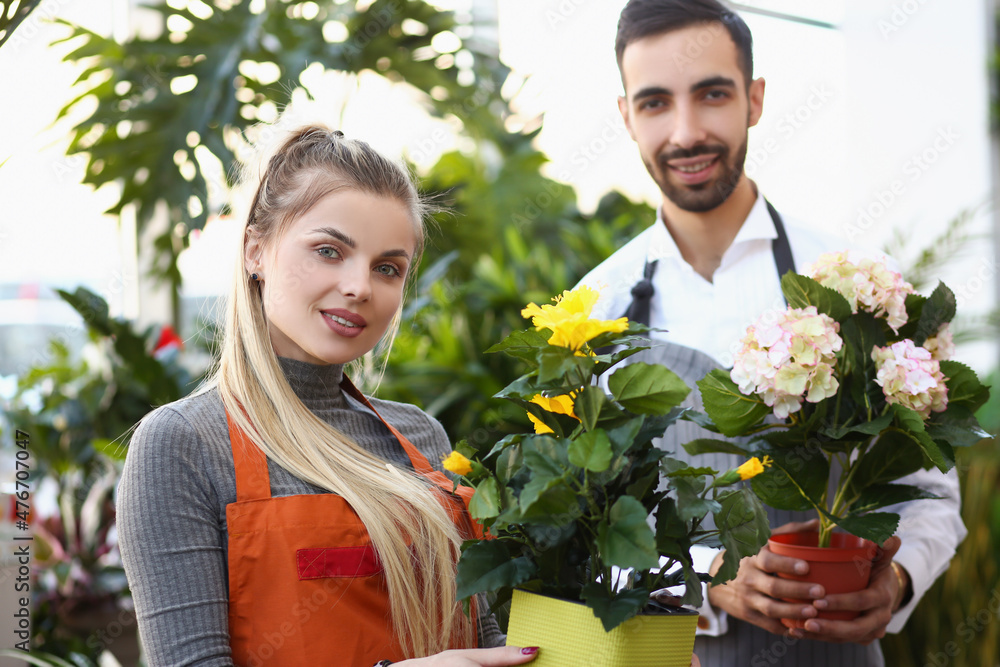 Cute florist workers hold flowers in pots, professional consultants ready to help with choice