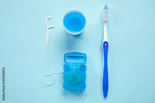 Dental floss, toothpick, rinse and brush on blue background