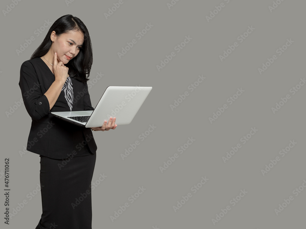 Young business woman holding laptop with finger on cheek Young business woman holding laptop with finger on cheek