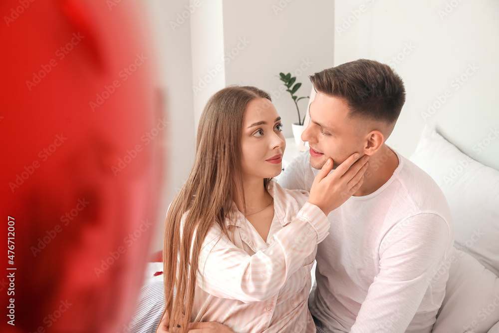 Happy couple celebrating Valentine's Day in bedroom at home Happy couple celebrating Valentine's Day in bedroom at home