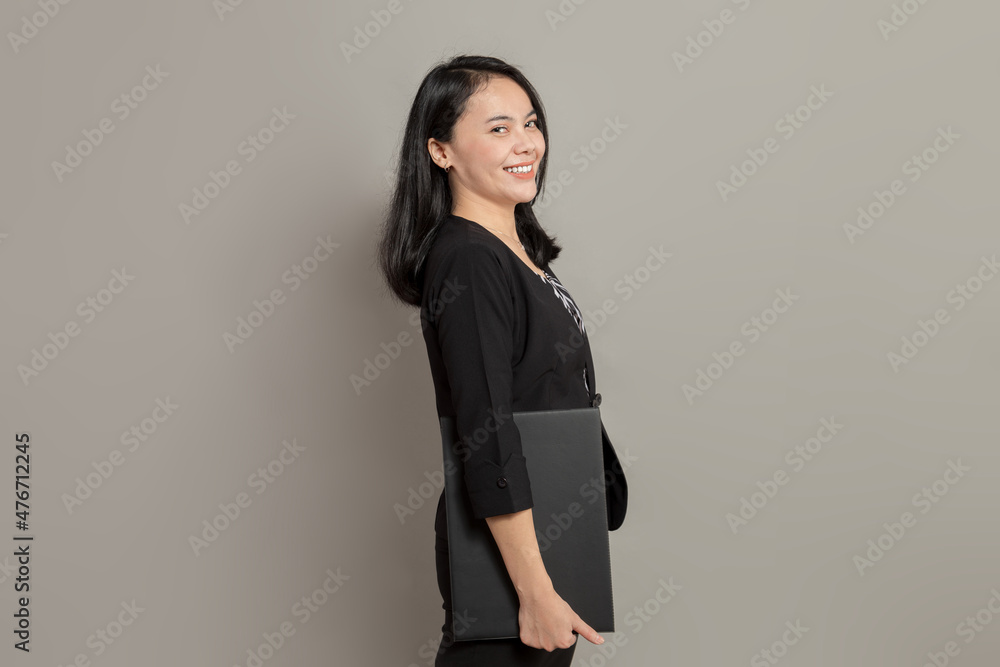 Young woman in a suit stands sideways while holding a folder Young woman in a suit stands sideways while holding a folder