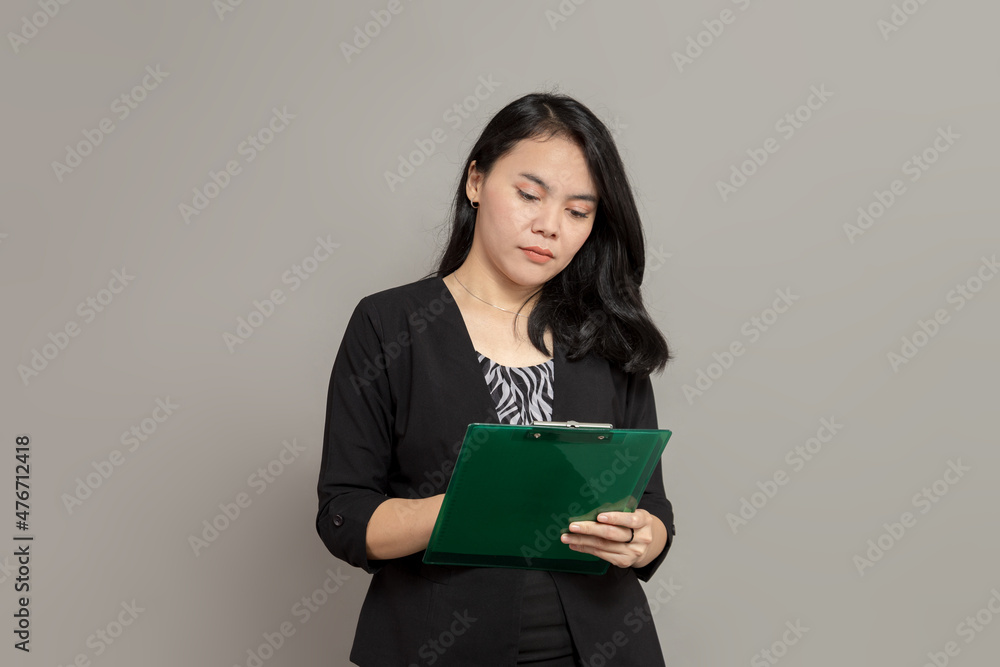 Business woman writing on clipboard with flat facial expression Business woman writing on clipboard with flat facial expression