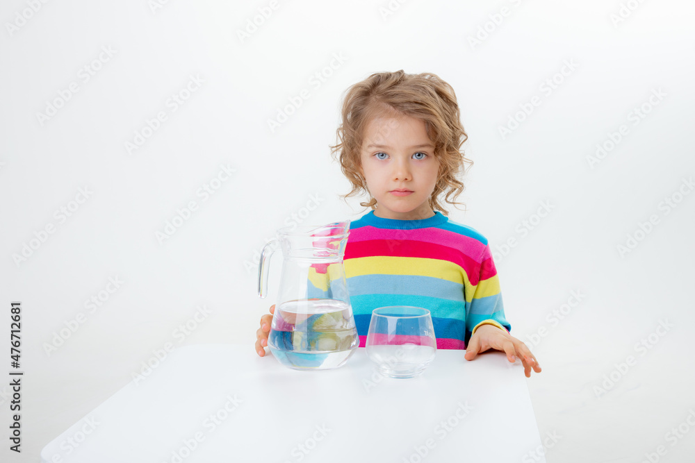a little cute girl holds a jug of water, pours water into a glass isolated on a white background a little cute girl holds a jug of water, pours water into a glass isolated on a white background