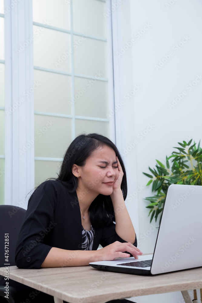 Business woman sitting on chair while closing her eyes in front of laptop Business woman sitting on chair while closing her eyes in front of laptop