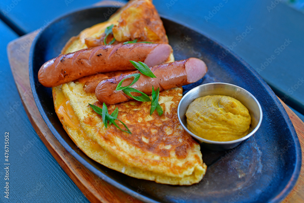 Delicious omelet with Bavarian sausages, restaurant serving.