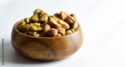 Dried fruits, hazelnuts, walnuts and almonds in a wooden bowl, light background.