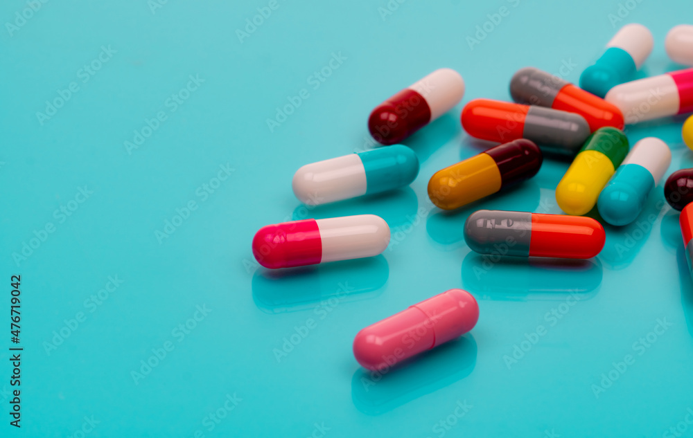 Antibiotic capsule pills on blue background. Prescription drugs. Colorful capsule pills. Antibiotic drug resistance concept. Pharmaceutical industry. Superbug problems. Medicament and pharmacology. Antibiotic capsule pills on blue background. Prescription drugs. Colorful capsule pills. Antibiotic drug resistance concept. Pharmaceutical industry. Superbug problems. Medicament and pharmacology.